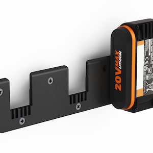 Puede incluir: Un soporte de pared negro con tres ranuras para sujetar baterías de litio 20V Max. El soporte tiene un tornillo en el lado izquierdo para sujetarlo a una pared. Una sola batería naranja y negra está en la ranura más a la derecha.