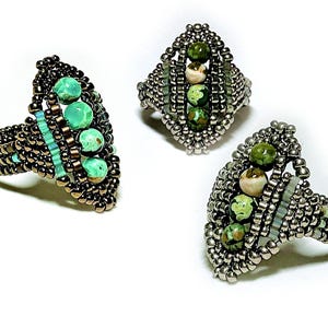 May include: Three rings crafted from metallic silver and bronze seed beads, each featuring a central vertical row of four round, variegated green and cream-colored stone beads. The beadwork creates an elongated, pointed oval shape for each ring.