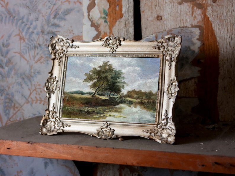 French landscape print in ornate frame displayed on a shelf, river scene with trees and sky, elegant classic wall decor for any room