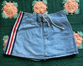 May include: A light blue denim skirt with a white drawstring waist and red and white stripes down the side.