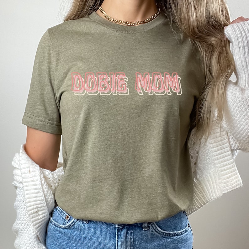 May include: A green t-shirt with the text "DOGGIE MOM" in pink outlined letters.