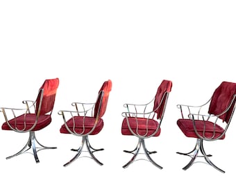 May include: Four swivel chairs with red velvet upholstery and chrome frames. The chairs have a unique design with a curved back and arms.