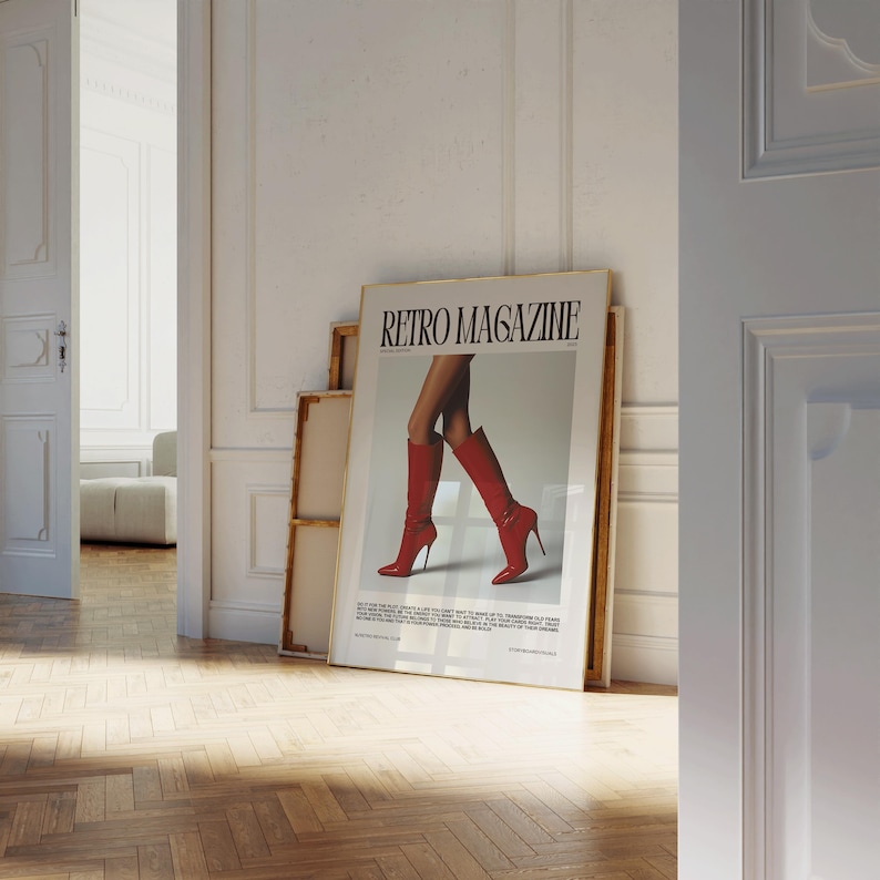 May include: A framed poster titled "Retro Magazine" featuring an image of a person's legs wearing red high-heeled boots. The poster is leaning against a wall in a room with a wooden floor and white walls.