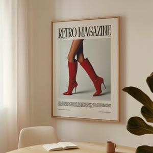 May include: A framed poster featuring the text "Retro Magazine" with a photograph of a person's legs wearing red high-heeled boots. The poster has a light wood frame and is hanging on a white wall.