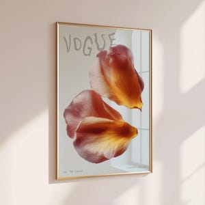 May include: A framed art print featuring the word "VOGUE" in light gray above two overlapping orange and pink flower petals. The print is in a gold frame and hangs on a light pink wall. The text "Limited Edition" is at the bottom.