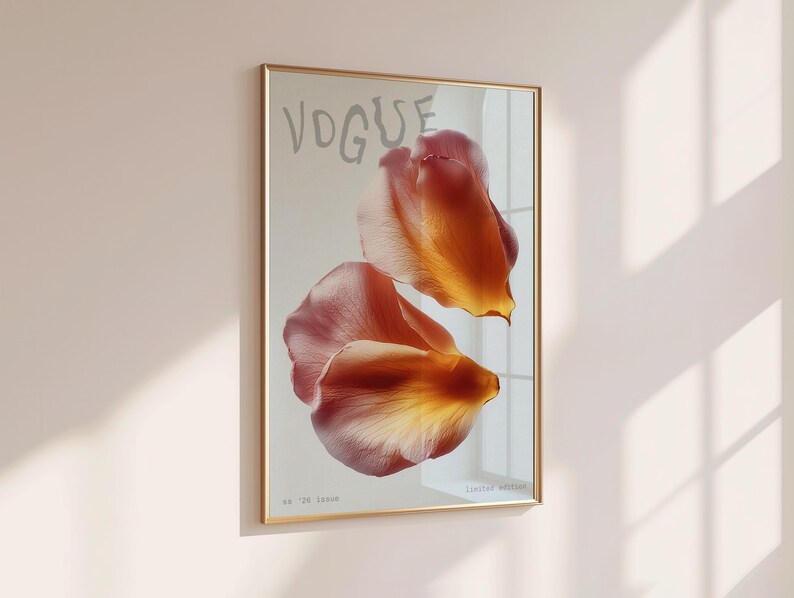 May include: A framed art print featuring the word "VOGUE" in light gray above two overlapping orange and pink flower petals. The print is in a gold frame and hangs on a light pink wall. The text "Limited Edition" is at the bottom.