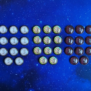 以下が含まれることがあります： 1、3、5の数字が書かれたゲームの駒のセット。駒は三角形に配置されており、1の駒が上、3の駒が中央、5の駒が下にあります。駒は緑、青、赤の3色です。