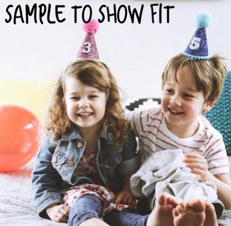 May include: Two children wearing birthday hats. The girl is wearing a pink hat with the number 3 on it. The boy is wearing a blue hat with the number 5 on it.