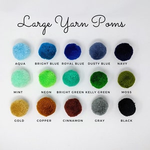 May include: A chart of 15 large yarn pom-poms in various colors, including aqua, bright blue, royal blue, dusty blue, navy, mint, neon green, bright green, kelly green, moss, gold, copper, cinnamon, gray, and black.
