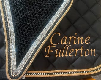 May include: Black quilted saddle pad with gold trim and silver rhinestone accents. The pad features the embroidered name "Carine Fullerton" in gold script. A black mesh material is visible at the top.
