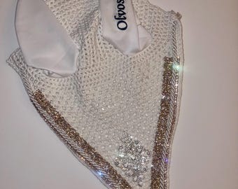 May include: White equestrian fly bonnet with ear covers. The bonnet features a sparkly gold and silver trim, a silver and crystal embellishment, and the name "Ofvossa" embroidered in navy blue.
