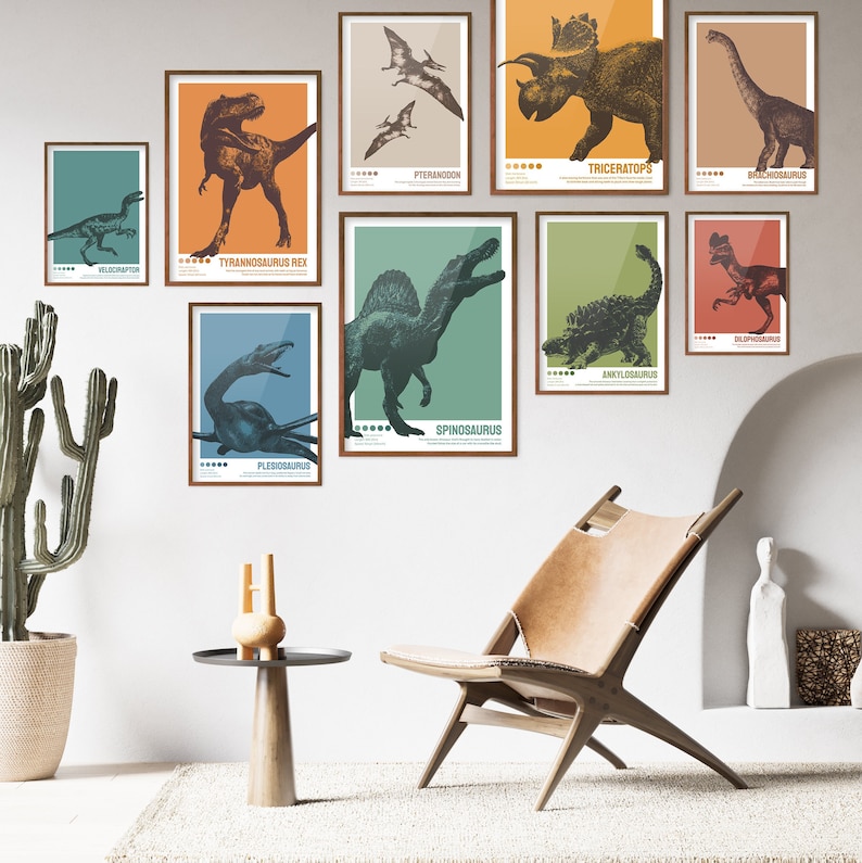 May include: A set of nine colourful dinosaur posters with illustrations of different dinosaurs, including Tyrannosaurus Rex, Triceratops, Velociraptor, and Spinosaurus. The posters are framed and hung on a white wall.