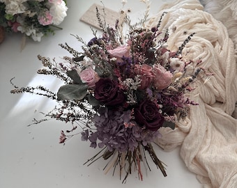 Könnte beinhalten: Ein Trockenblumenstrauß mit einer Mischung aus rosa, lila und burgunderfarbenen Blüten. Der Strauß ist mit Schnur gebunden und enthält getrocknete Gräser und Zweige.