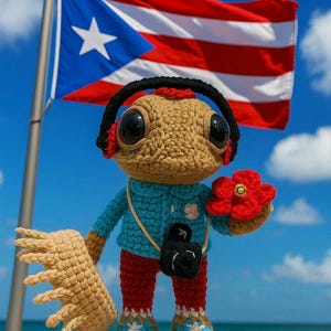 May include: A crocheted figure with large eyes, wearing a blue jacket, red trousers, and blue shoes. It holds a red flower and a beige fan. A black camera hangs around its neck. The Puerto Rican flag waves in the background.