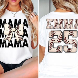 May include: White t-shirt with "MAMA" in black block letters and a baseball bow graphic. The back of the shirt features the name "EMMA" and the number "25" in a baseball stitch design. A casual, sporty style.