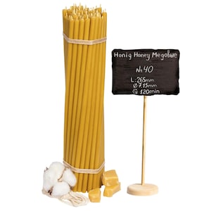Könnte beinhalten: Ein Bündel aus 40 gelben Bienenwachskerzen, 67,3 cm lang und 1,82 cm im Durchmesser. Die Kerzen sind mit einer Schnur zusammengebunden und werden von einem kleinen Schild aus Schiefer begleitet, auf dem "Honig Honey Megobbe No. 40 L: 265mm Ø 7.15mm G 120min" steht.