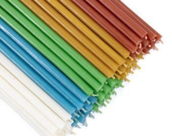 May include: A bundle of colorful beeswax candles arranged in a rainbow pattern. The candles are white, light blue, green, yellow, orange, and red.