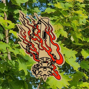 May include: A tan-colored sticker featuring a stylized illustration of a tower engulfed in red flames. The tower has a small window and is connected to a spiked ball by chains. The design has a tattoo-inspired aesthetic.