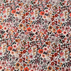 May include: A close-up of a floral fabric with a white background. The fabric is densely covered with small flowers in shades of red, orange, pink, and purple, with green leaves. The overall effect is a vibrant, colorful pattern.