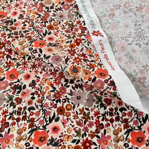 May include: Floral fabric featuring a cream backdrop and a pattern of red, orange, pink, and burgundy flowers. The fabric is folded, revealing a second fabric with a similar floral pattern. The text "Aquarelle Fleurs" and "Digital Collection designed for you by POP" is visible.