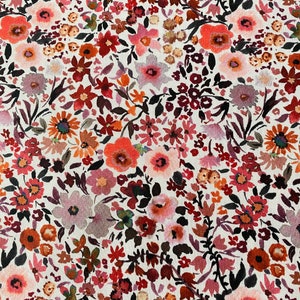 May include: A fabric with a detailed floral print. The pattern is composed of numerous small flowers in hues of red, orange, pink, and purple, set against a white backdrop. The flowers are of different sizes and shapes, creating a textured and visually rich surface.