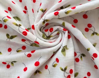 May include: White fabric with a repeating pattern of red cherries and green leaves. The cherries are a vibrant red, and the leaves are a muted green. The fabric is tightly swirled, showing the texture and pattern.