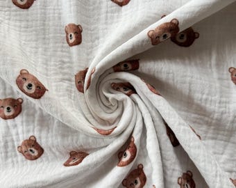 May include: White fabric with a repeating pattern of brown bear faces. The fabric is folded and textured.