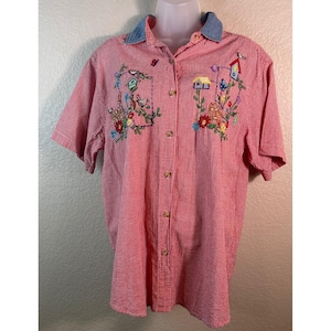 May include: A short-sleeved button-down shirt featuring a red and white gingham pattern. The shirt has a light blue collar and embroidered designs on the chest depicting birdhouses, flowers, and small birds in various colors.