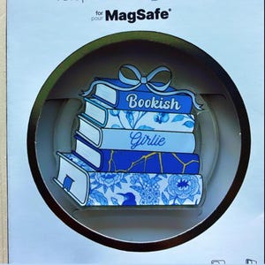 May include: A blue and white decorative phone grip featuring a stack of books. The books have floral and geometric patterns, with the words "Bookish" and "Girlie" on them. The grip is designed for MagSafe.