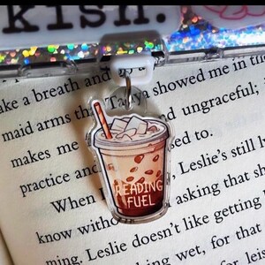 May include: A clear plastic bookmark with a cartoon illustration of a brown and white iced coffee drink. The drink has a straw and the text "Reading Fuel" on the cup.