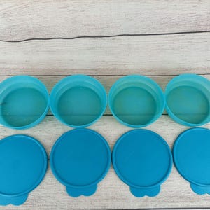 Könnte beinhalten: Satz mit sieben blauen Plastikbehältern mit Deckeln. Die Behälter sind rund und haben eine glatte Oberfläche. Die Deckel sind ebenfalls rund und haben eine glatte Oberfläche.