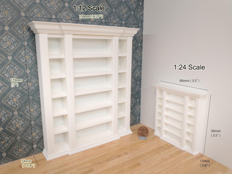 May include: Two white miniature bookshelves, one larger than the other. The larger bookshelf is 6.25 inches tall and 7 inches wide. The smaller bookshelf is 3.5 inches tall and 3.5 inches wide. Both bookshelves have five shelves each.