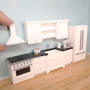 May include: White miniature kitchen set with a stove, oven, sink, cabinets, and a refrigerator. The kitchen is made of plastic and is designed for dollhouses.