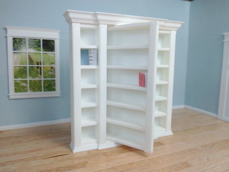 May include: White bookcase with a door that swings open to reveal shelves. The bookcase has a decorative trim around the top and sides. The shelves are empty except for a single book on the top shelf.
