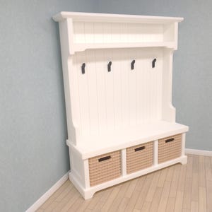 May include: White wooden entryway bench with a shelf and three storage baskets. The bench has four hooks on the back.