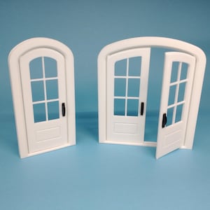 Könnte beinhalten: Zwei weiße, gewölbte Türrahmen mit Glasscheiben und schwarzen Türklinken. Eine Tür ist geschlossen, die andere ist offen.