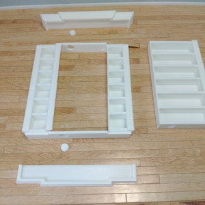 May include: White, unassembled, wooden shelf unit with multiple compartments. The shelf unit is made of several pieces that can be assembled to create a variety of configurations.