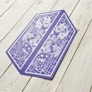 May include: A purple hexagon-shaped sticker with a white floral design. The design features a repeating pattern of flowers, leaves, and vines. The sticker has a geometric border.