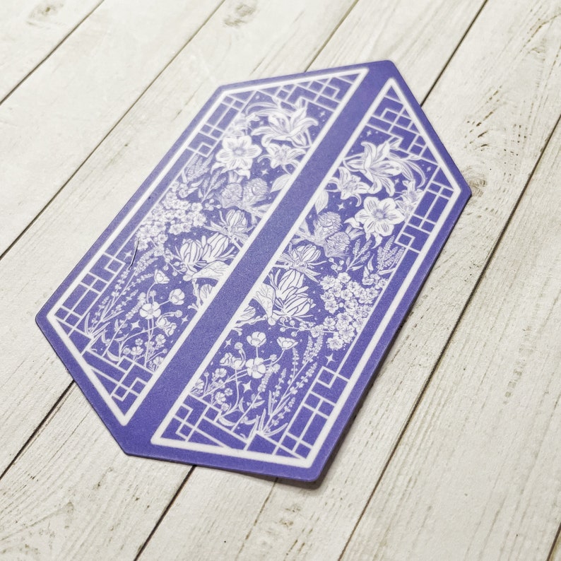 May include: A purple hexagon-shaped sticker with a white floral design. The design features a repeating pattern of flowers, leaves, and vines. The sticker has a geometric border.