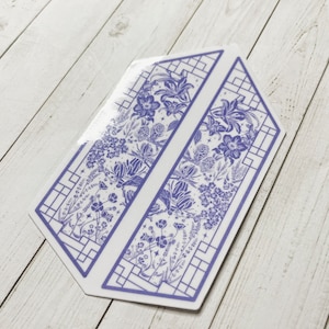 May include: A pair of blue and white floral patterned bookmarks with a geometric design. The bookmarks are shaped like a long rectangle with a pointed end.