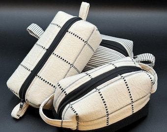 May include: Three toiletry bags with black and white checkered patterns. The bags have black zippers and handles.