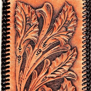 May include: A brown leather wallet with a tooled floral design. The wallet has a black stitched border.
