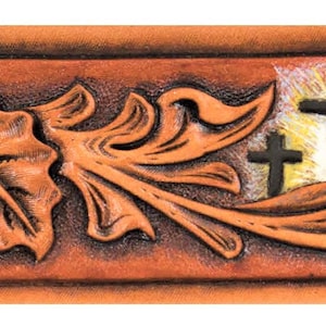 May include: A brown leather belt with a tooled design featuring a fish, leaves, crosses, and a flower. The design is in shades of brown and white.