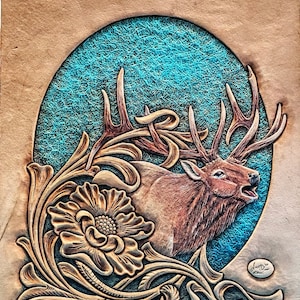 May include: A brown leather carving of an elk with large antlers, surrounded by floral designs. The background is a teal blue color.