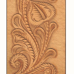 May include: A detailed floral design carved into a piece of brown leather. The design features intricate swirls and leaves.