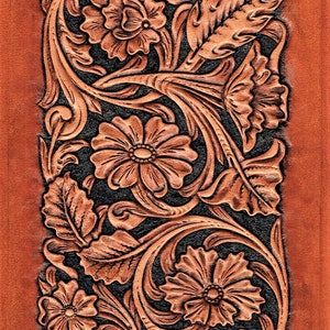 May include: A brown leather background with a detailed floral design carved into the surface. The design features intricate leaves, flowers, and swirls in a dark brown colour.