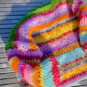 Puede incluir: Un su&eacute;ter de punto de rayas de colores con una textura peluda. El su&eacute;ter est&aacute; hecho con una variedad de colores, incluyendo rosa, verde, amarillo, naranja y azul.