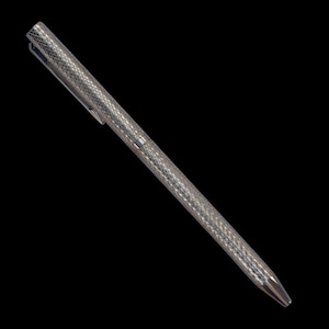 Puede incluir: Un bol&iacute;grafo de tono plateado con un patr&oacute;n de diamantes entrecruzados en todo el cuerpo cil&iacute;ndrico y la tapa. El bol&iacute;grafo incluye un clip de bolsillo delgado integrado en la tapa y una punta c&oacute;nica lisa y afilada.