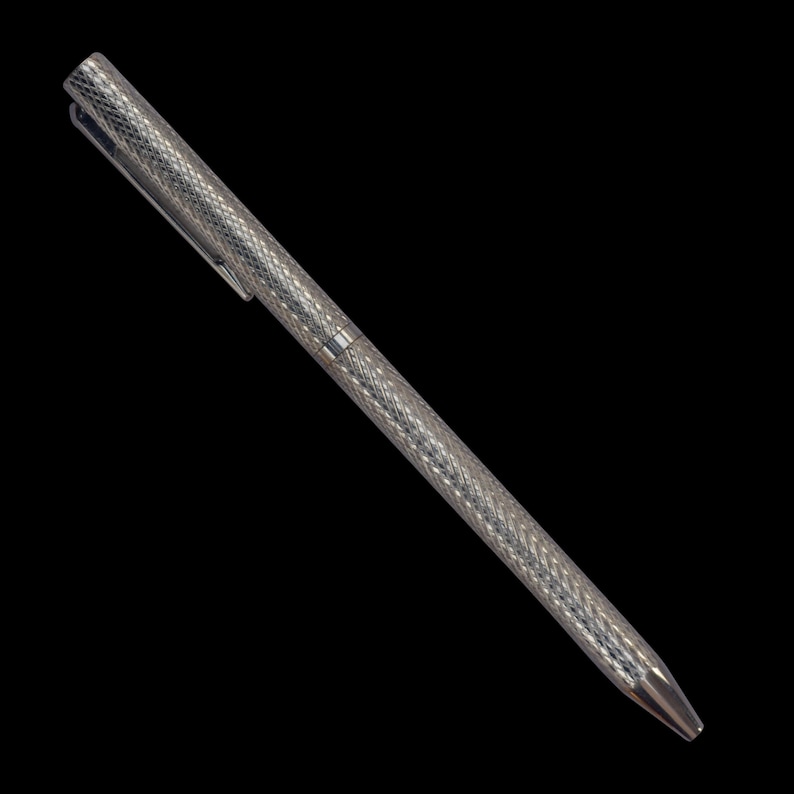 Puede incluir: Un bol&iacute;grafo de tono plateado con un patr&oacute;n de diamantes entrecruzados en todo el cuerpo cil&iacute;ndrico y la tapa. El bol&iacute;grafo incluye un clip de bolsillo delgado integrado en la tapa y una punta c&oacute;nica lisa y afilada.