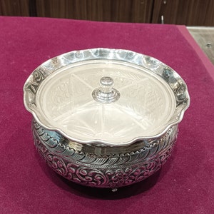 May include: A silver serving dish with a lid and four compartments. The dish is decorated with intricate floral designs.